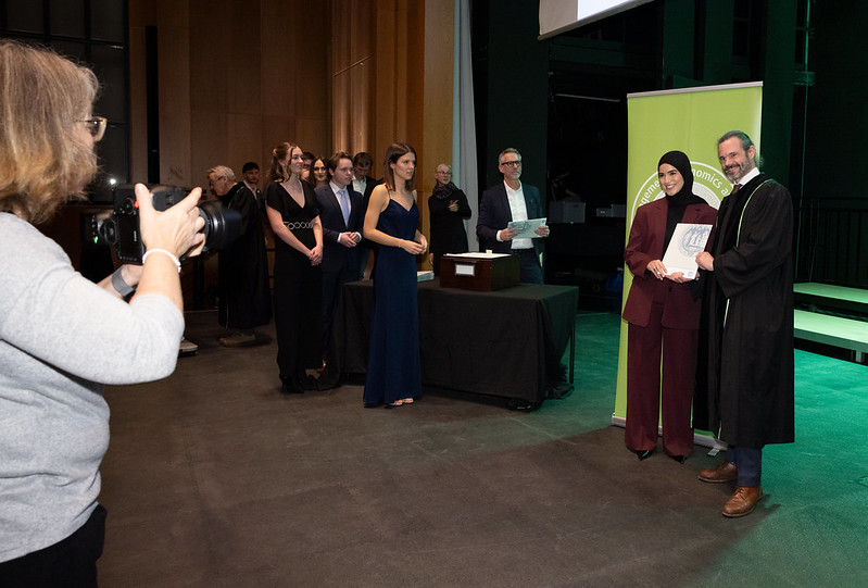 Auf der Bühne der Aula werden Handshake-Fotos mit den Professor:innen der Fakultät gemacht.