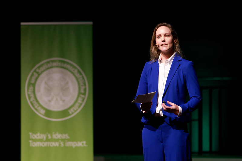 Alumna speaking on stage during graduation ceremony