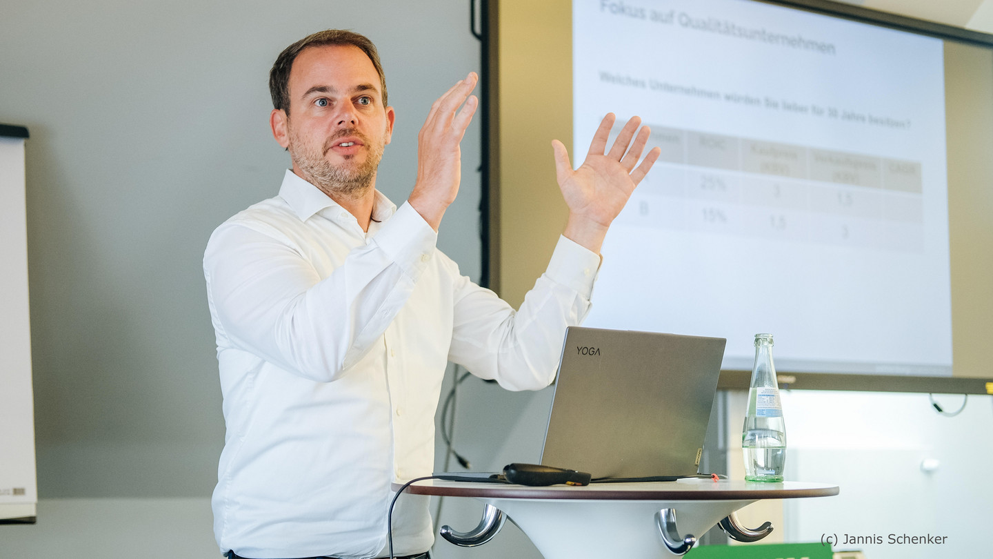 Florian Sonnenburg gives a lecture at a step desk during a seminar in a white shirt.