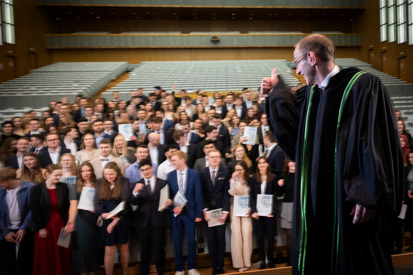Vor dem Gruppenfoto in der Aula gratuliert Professor Ulrich Thonemann, PhD, den Absolvent:innen