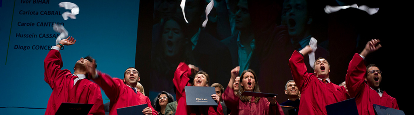 Absolventen in roten Roben auf einer Bühne werfen ihre Schals in die Luft