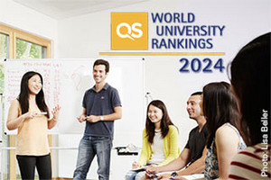 Zwei fröhlich lächelnde Studierende vor einem flipchart präsentieren einer im Halbkreis das rechte Bilddrittel füllenden Gruppe sitzender, mitschreibender Studierender. Tex: "QS World University Rankings 2024"