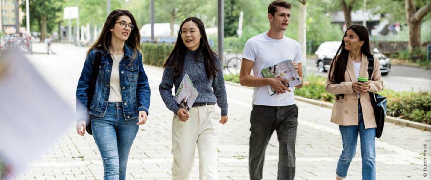 Four students, corresponding to the four values of the WiSo faculty, strolling in front of the WiSo extension building