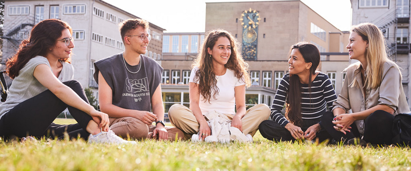 Bachelor Volkswirtschaftslehre der WiSo-Fakultät - Junge Menschen mit Laptops und Büchern sitzen auf der Kölner Uniwiese