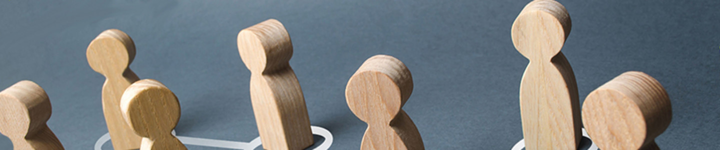Wooden figures on a grey surface, connected with a symbolic network of white lines