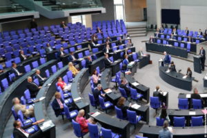 Der Bundestag, Podium vorne, Leute sitzen über den Raum verteilt