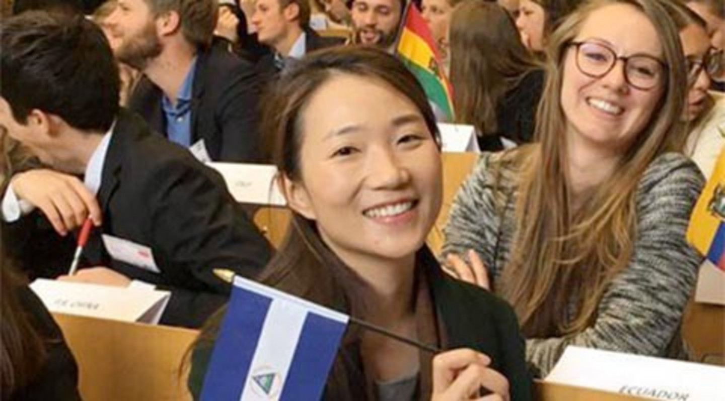 Sui Kahn in a lecture hall bank holding a flag of Nicaragua