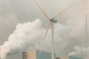 Windturbine vor aufsteigendem Rauch im Industriegebiet
