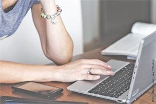 Hand of a young women on a Laptop Elbow propped up
