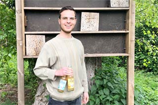 Vernon Flassak with two bottles of icetea in front of a bee-hotel