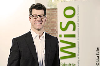 Professor Doktor Wolfgnag Ketter vor einer Wand mit "WiSo"-Schriftzug