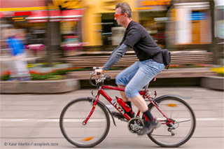 A man on a red bicycle riding through a pedestrian zone