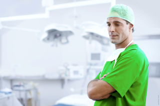 Doctor in green scrubs. Arms crossed. Looks friendly and approachable.