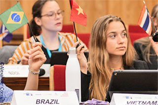 Teilnehmerinnen des 15. CEMS Model UNFCCC Roleplays in Köln winken mit Fähnchen zur Abstimmung