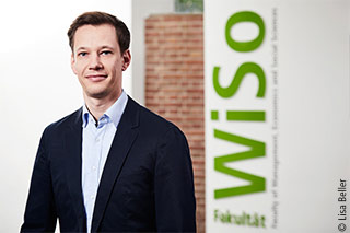 Prof. Dr. Erik Hornung in front of a WiSo logo at the University of Cologne