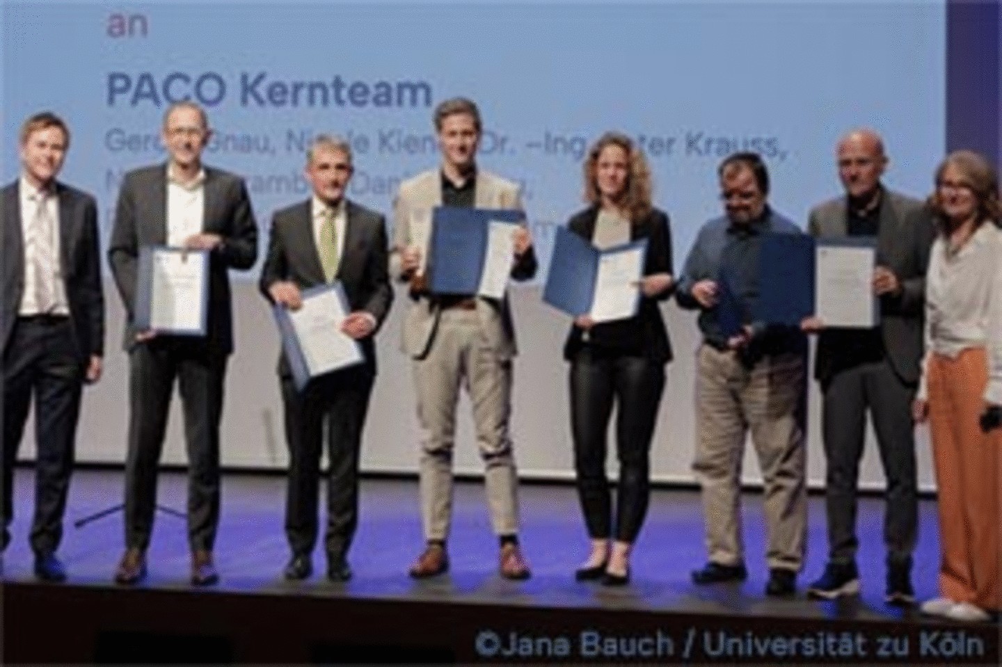 Gruppenfoto des PACO-Kernteams der Wirtschafts- und Sozialwissenschaftlichen Fakultät der Universität zu Köln mit Urkunden auf der Bühne bei der Verleihung des Universitätspreises 2025